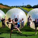 a group of people jumping in inflatable balls on the grass