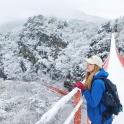 a woman standing on a suspension bridge in the snow