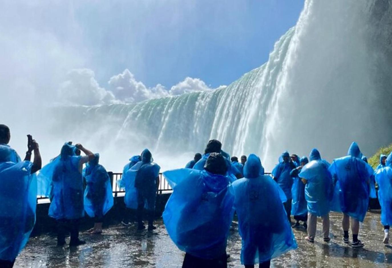 Un grupo de personas de pie frente a una cascada.