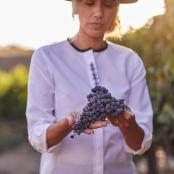 a woman is holding a bunch of grapes