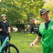 two men standing in a park with a bike
