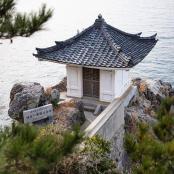 a small building on the rocks near the water