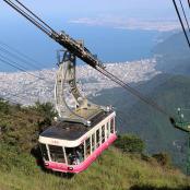 a pink and white cable car going up a mountain