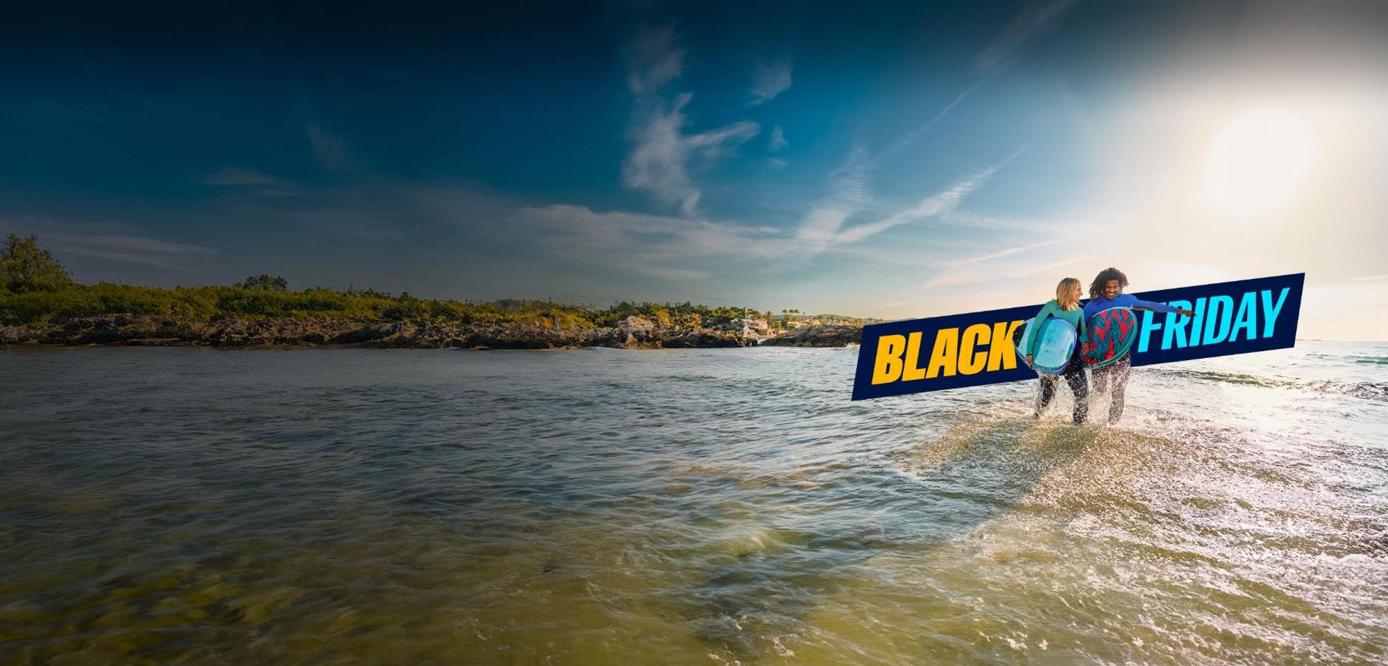 Λογότυπο Black Friday και δύο άτομα με σανίδες bodyboard στην παραλία