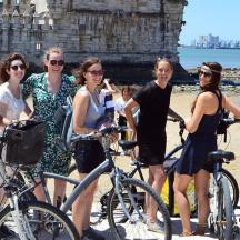 a group of women standing on the beach with bikes