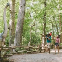 un grup de persones mirant una girafa i un dinosaure