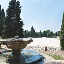 a fountain in the middle of a park with trees