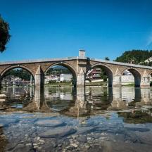un pont de pedra sobre un riu amb reflexos a l'aigua