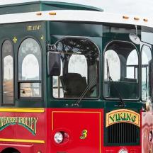 a red and green trolley car parked in a parking lot