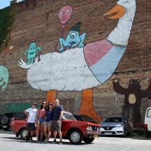 a group of people standing in front of a wall with a chicken