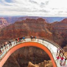 a group of people walking on a bridge over the grand canyon