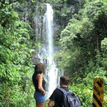 a man and a woman standing in front of a waterfall