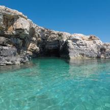a cave in the water next to a rocky cliff