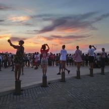 a group of people standing around watching the sunset