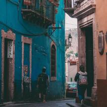 two people walking down a street in a blue building