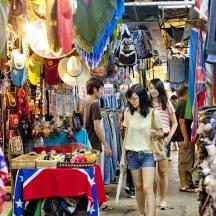 một nhóm người đang đi bộ qua một khu chợ