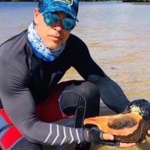 un home amb un vestit de neoprè que sosté un animal mort