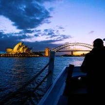 a person on a boat in the water with a view of the opera house