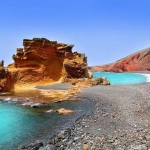 ein Strand mit Felsen und Wasser und einer Klippe