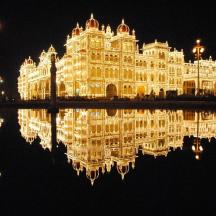 a large building with its reflection in the water at night