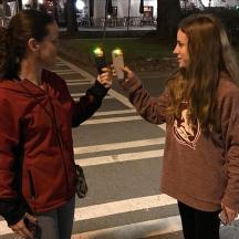 two girls are holding lit candles on a street