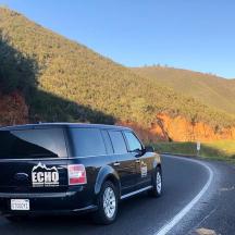 a black suv is driving down a road