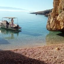 мали чамац у води поред литице