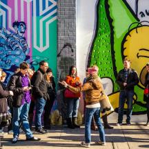 a group of people standing in front of a wall with graffiti