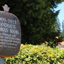 a sign in front of a hedge with a bush