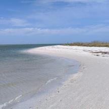 a white beach with the ocean in the background