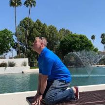 a man sitting on a bench in front of a fountain