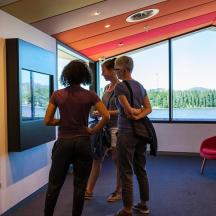 a group of people standing in a room looking at a wall