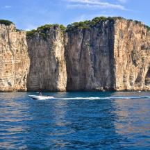 a boat in the water next to a large cliff