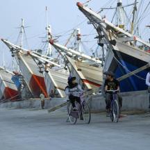 a group of people riding bikes in front of boats