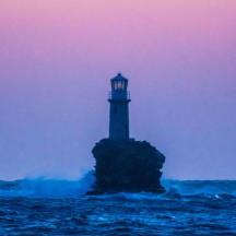 un faro situato su una roccia nell'oceano