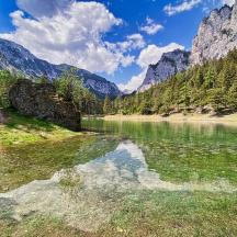 una massa d'aigua amb arbres i muntanyes al fons