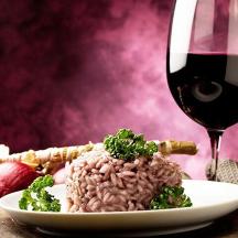 a glass of wine next to a plate of rice and broccoli
