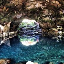eine Höhle mit einem Wasserbecken davor