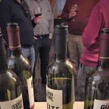 eine Gruppe von Menschen steht um drei Flaschen Wein herum