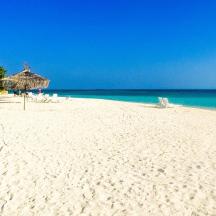 a beach with an umbrella and chairs and the ocean