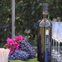 a bottle of wine sitting next to glasses and grapes