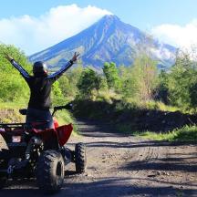 a person on a four wheeler on a dirt road with their arms up