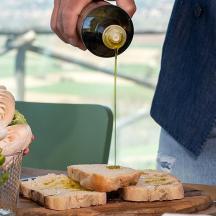 a person pouring a drink into a sandwich and bread