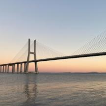 a bridge over a body of water with the sun setting