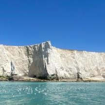 a large cliff next to a body of water