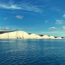 a large body of water with white cliffs in the background