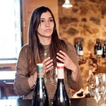 una dona asseguda a una taula amb dues ampolles de vi