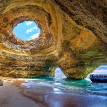 a boat in the water in front of a rock cave