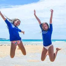 two girls jumping in the air on the beach
