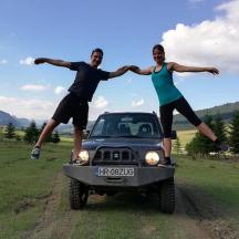 a man and a woman jumping in front of a jeep